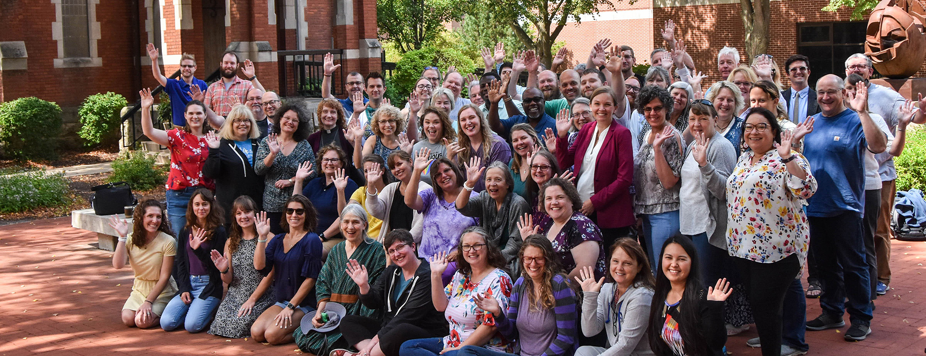 Large group of smiling UDTS students and faculty waving