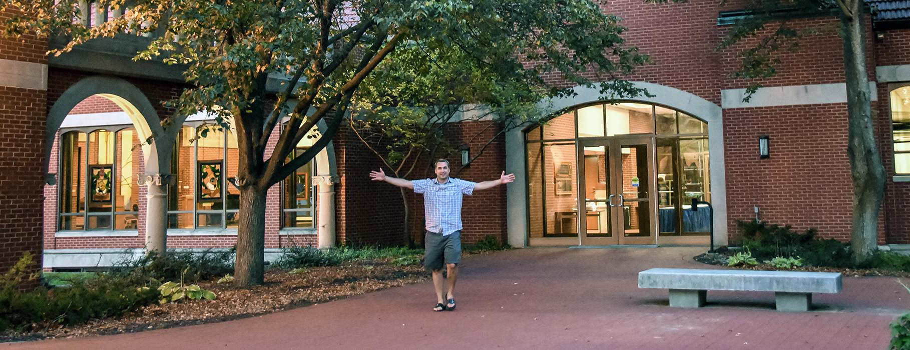 Man with outstretched arms in Alumni Courtyard at UDTS