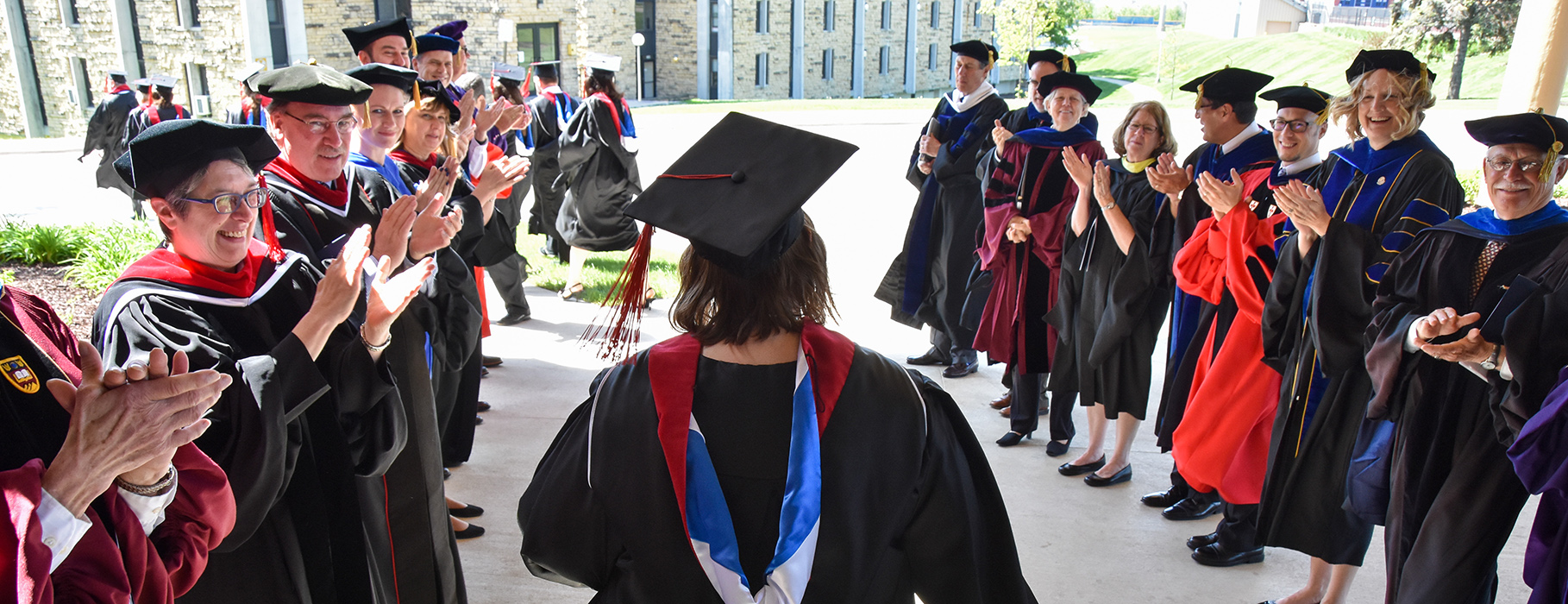 Faculty in regalia applauding graduates at UDTS commencement ceremony