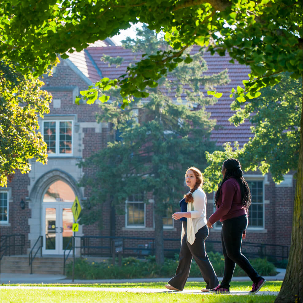 Two females walk on UD quad on a sunny day